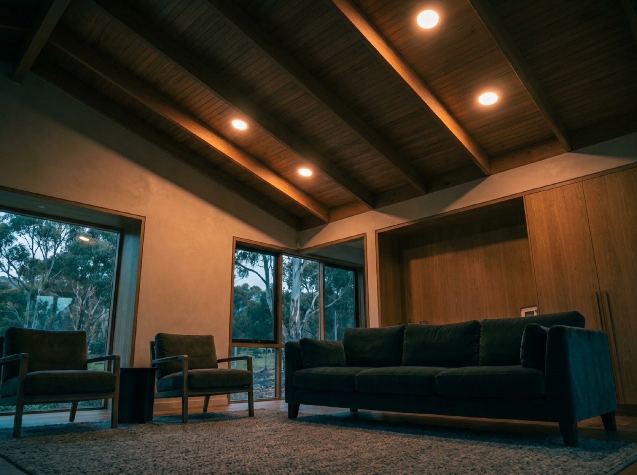 A living room lit by warm recessed downlights at dusk