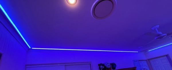 A ceiling fan and a strip of blue LED lighting running along a ceiling line
