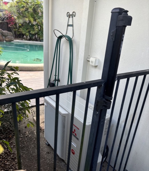 An outdoor air conditioning condenser unit beside a swimming pool