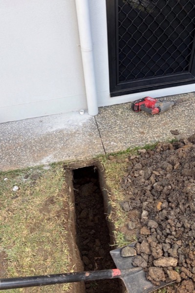 A narrow trench dug beside the wall of a house