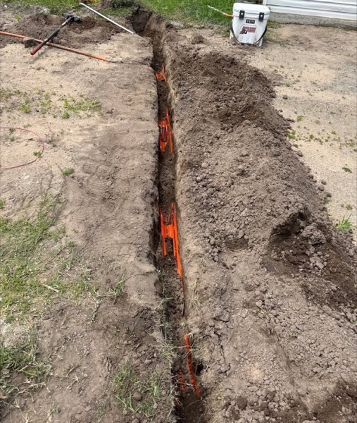 Orange conduit sitting in an open trench
