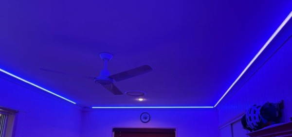 A run of LED strip lighting along a ceiling beside a ceiling fan