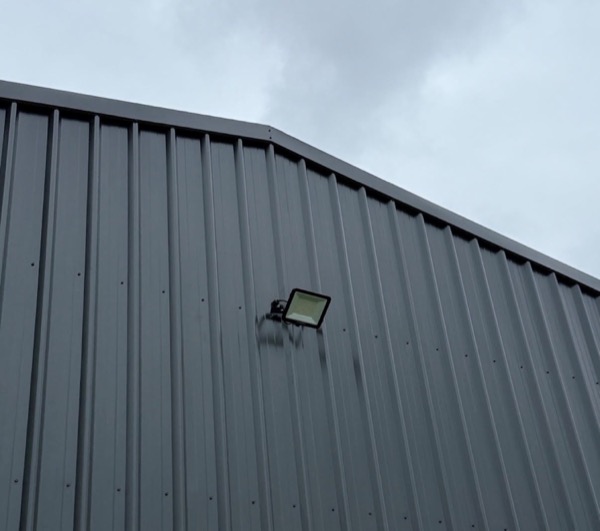A flood light mounted high on the outside wall of a shed