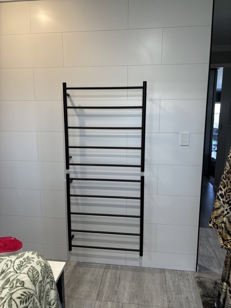 A heated towel rail mounted on a bathroom wall