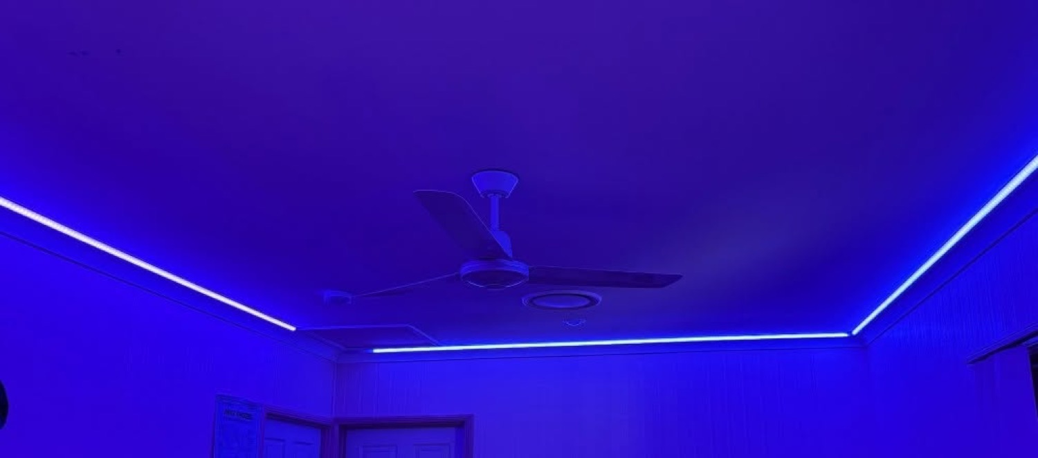 A strip of LED lighting running along a ceiling line in a dark room
